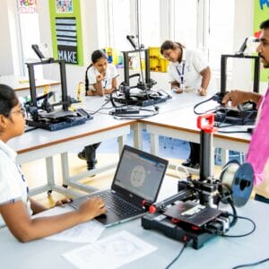 Three students are learning to work with 3D printing machine under the guidance of a senior teacher in a private school in Chennai.
